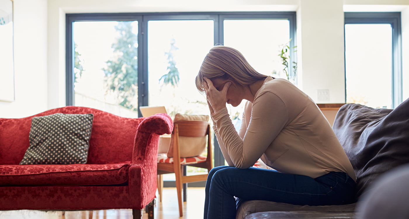 a woman sitting on a couch with her face in her hands