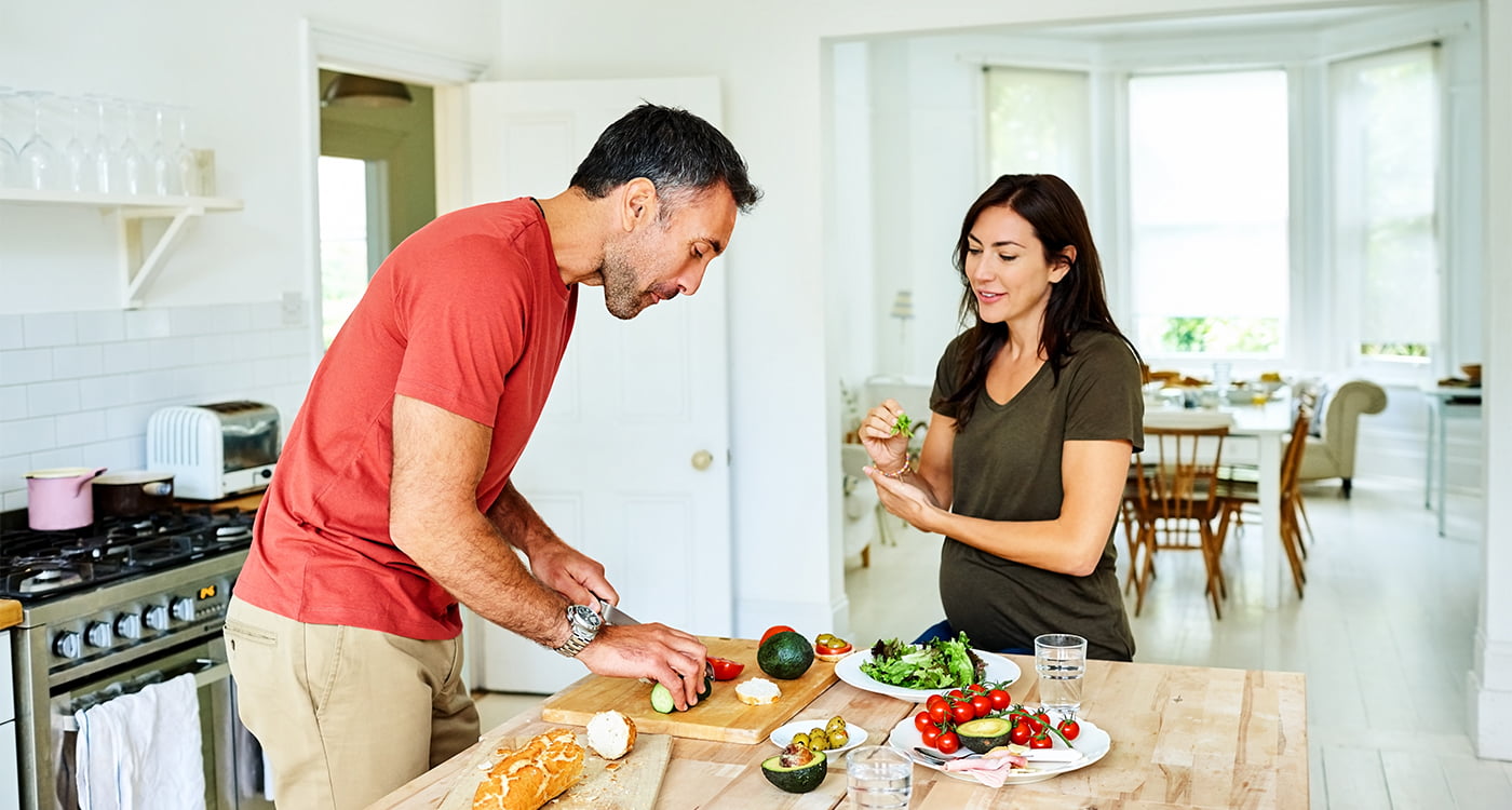 man and woman in the kitchen cutting vegetables